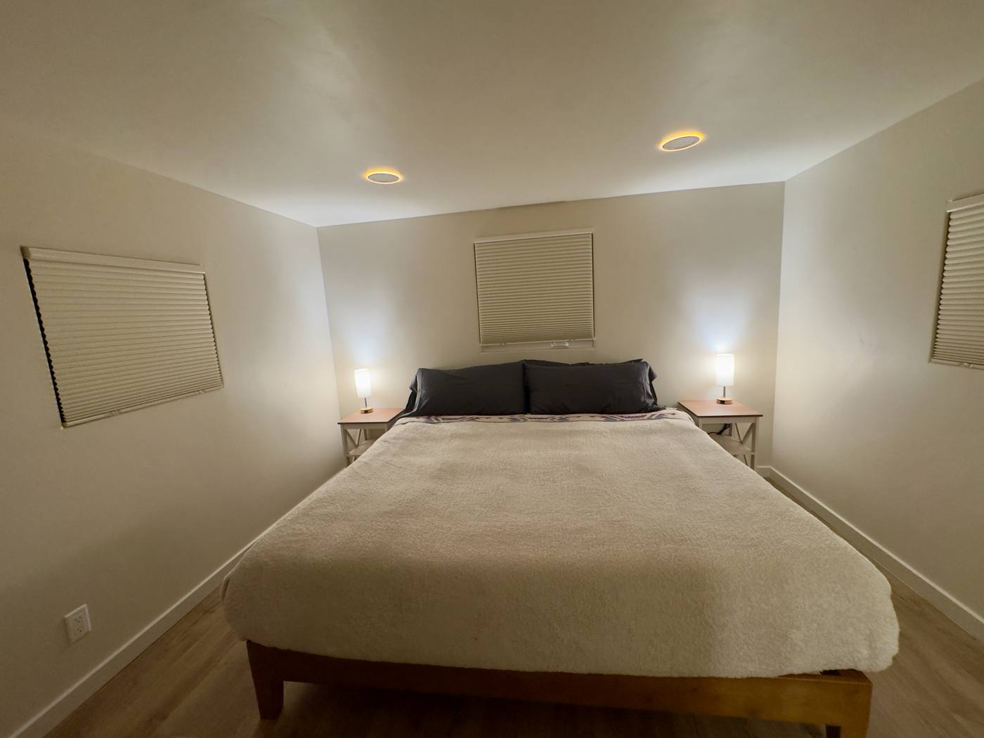 The same bedroom at night with the blackout blinds down and the bedside lamps lit