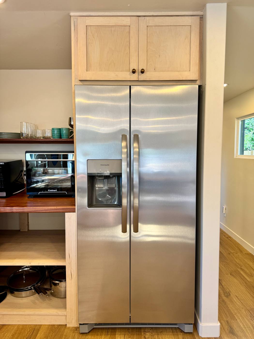 Side-by-side refrigerator with ice and water dispenser, maple cabinets, microwave alongside