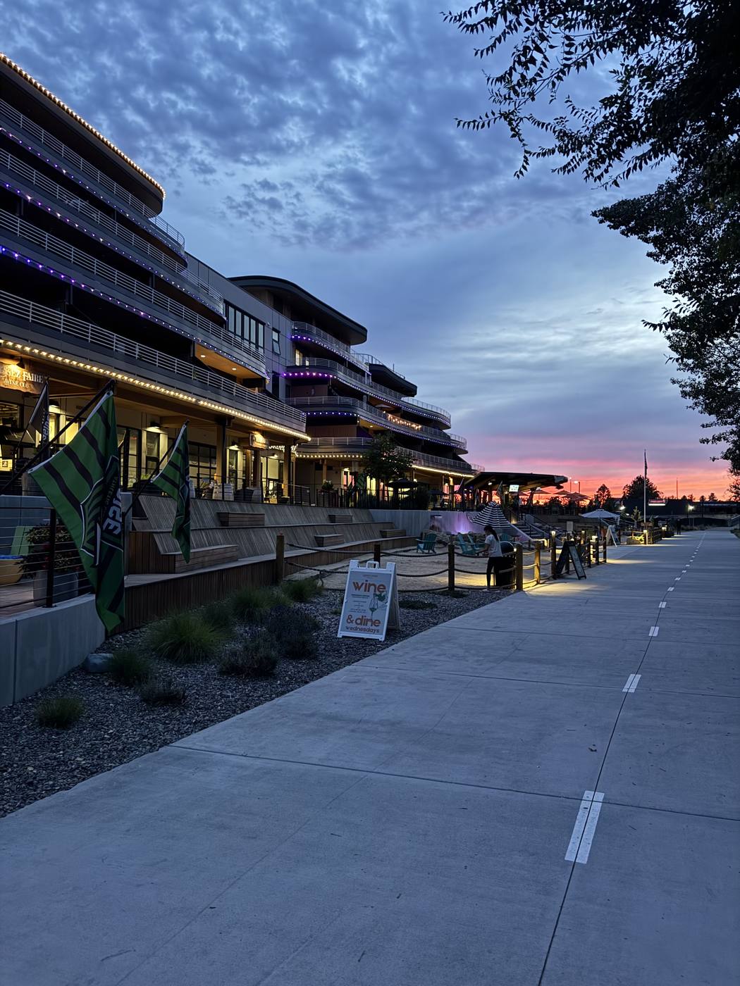 The Boardwalk at dusk seen from the Greenbelt path, string lights along the terraces