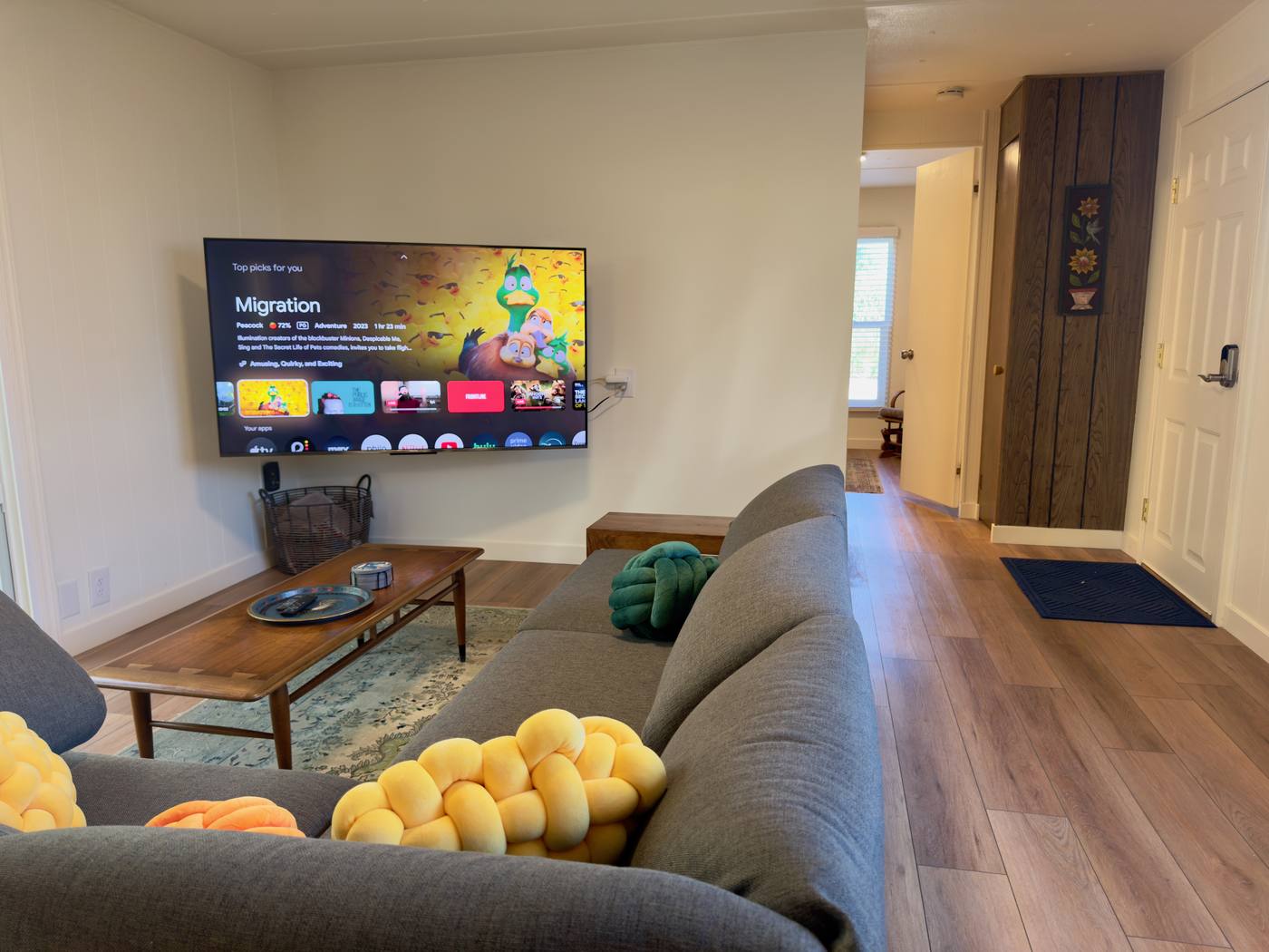 Living room with a sectional sofa, coffee table and wall-mounted TV beside the entry door